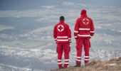 Salzburg, Austria - December 30, 2013: Two rescuers look down at the city of Salzburg from the Gaisberg. Is the emblem of the Red Cross on her back. From the summit of the mountain is a paragliding take-off and landing area. Again and again happen at this place accidents. So also on this day.